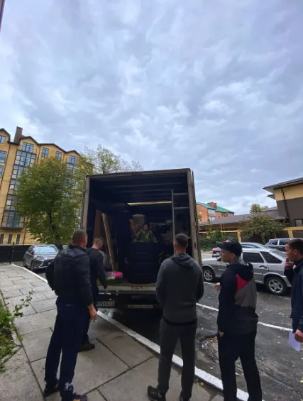 Бригада грузчиков у открытого фургона во дворе